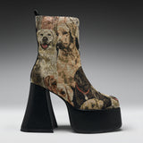 A high-heeled ankle boot with a black platform sole and block heel, featuring a woven or printed pattern of various dog portraits in beige, brown, and black tones.