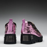 A pair of metallic pink high-top sneakers with chunky black platform soles, studded details, and purple pull tabs, shown from the back against a dark gray gradient background.
