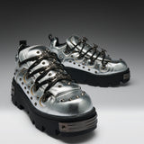 A pair of metallic silver high-top sneakers with black platform soles, black laces, and silver studs, displayed on a dark-to-light gray gradient studio background.