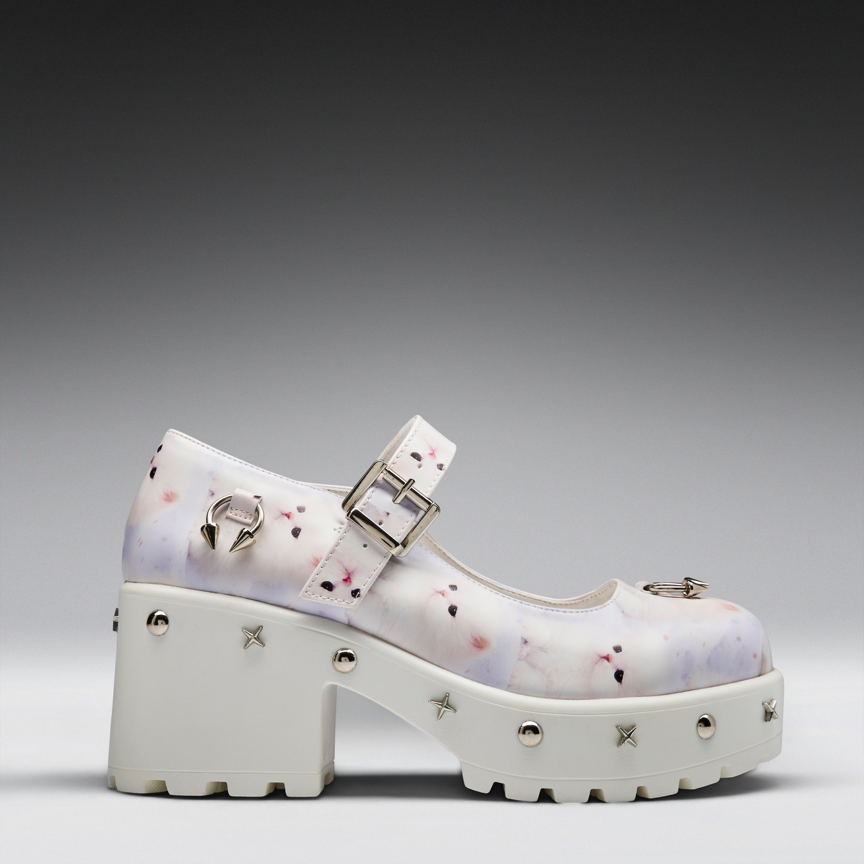A white platform Mary Jane shoe with a subtle pastel watercolor pattern, silver-tone buckles, and decorative metal studs on a gray gradient background.