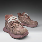 Pair of brown hiking boots with white laces on a gray background