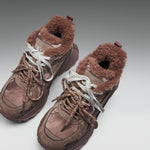 Pair of brown winter boots with fur lining on a light gray background