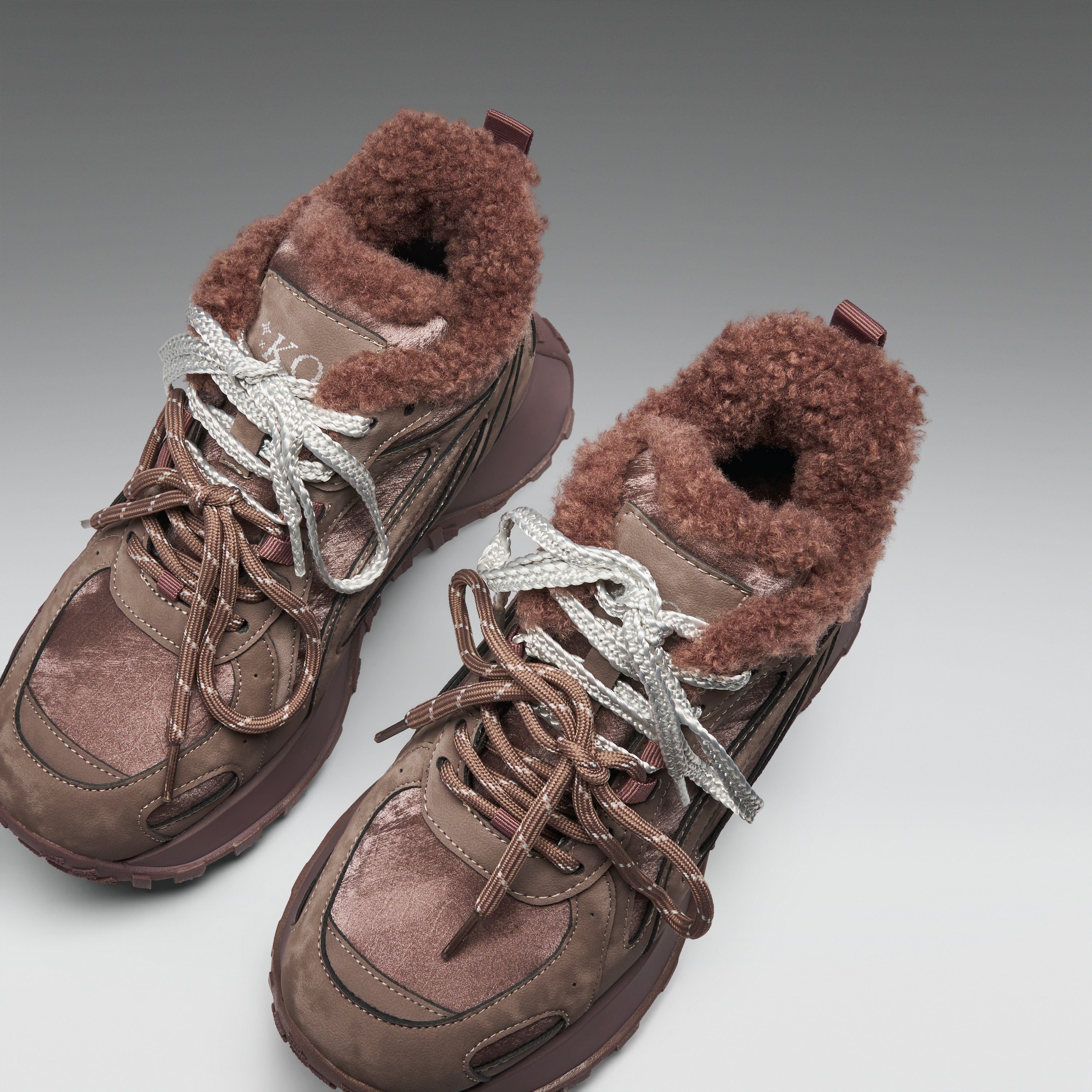 Pair of brown winter boots with fur lining on a light gray background