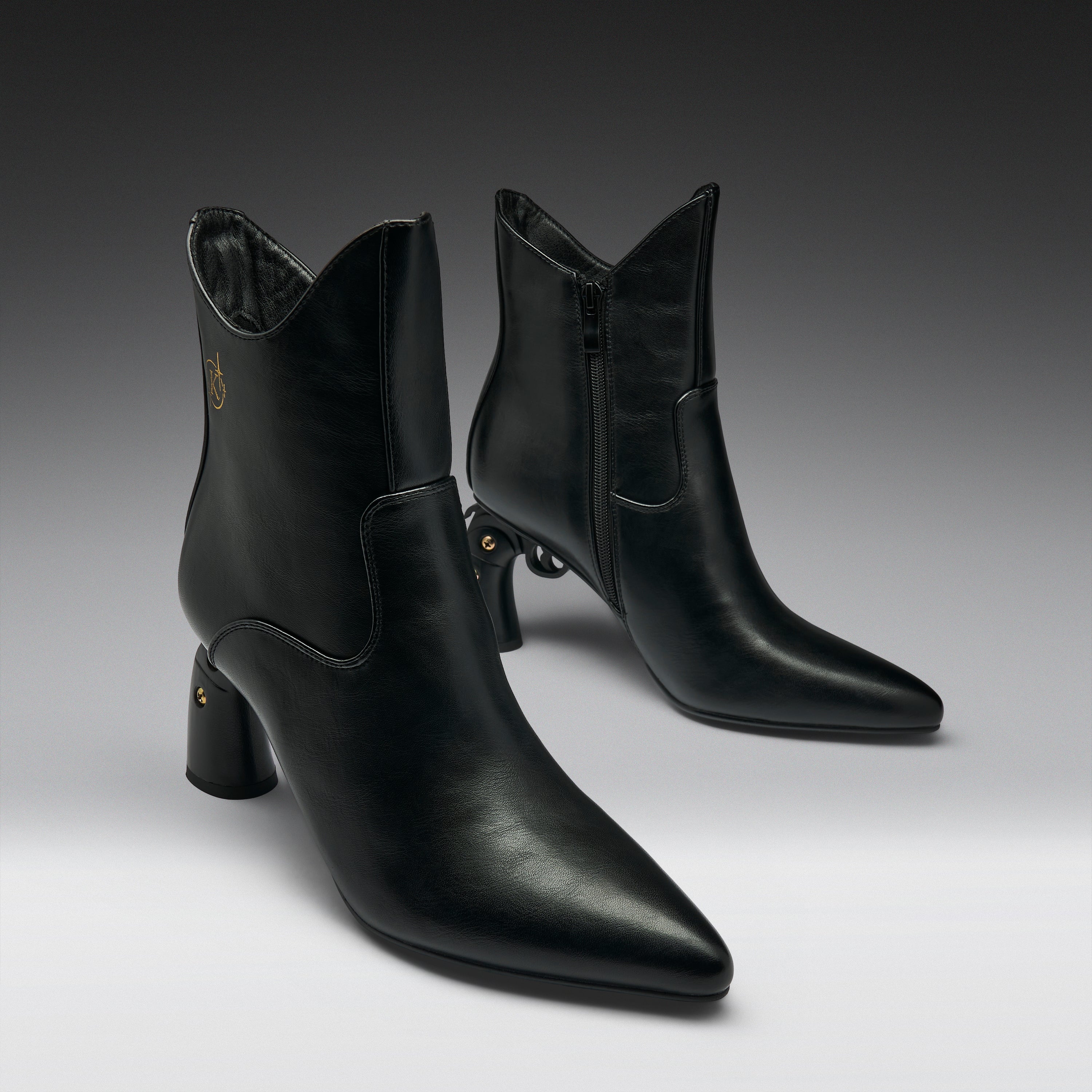 A pair of black leather ankle boots with pointed toes and block heels, displayed on a clean gray gradient studio background.