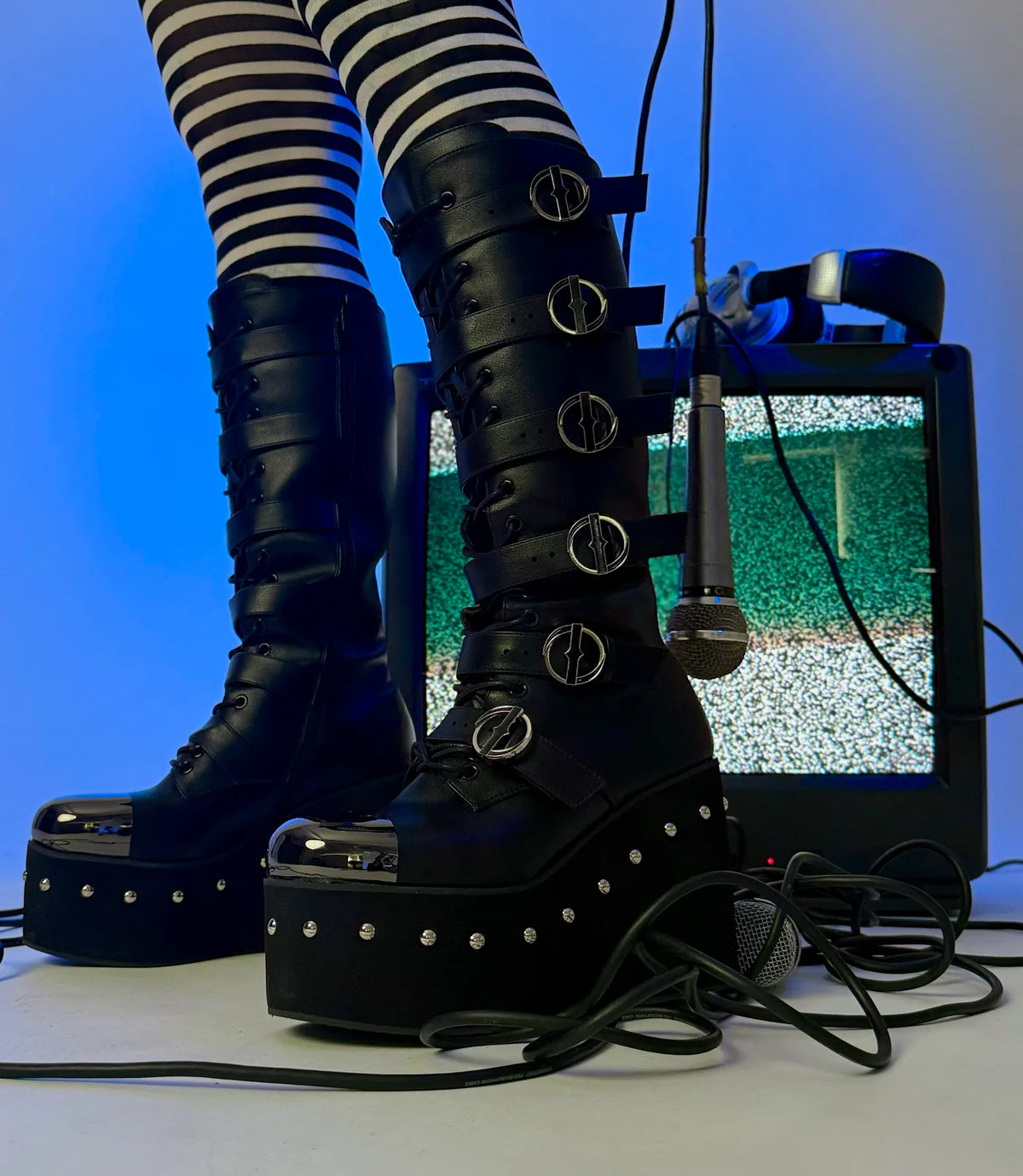 Immortal Platform Long Boots on set with a static TV